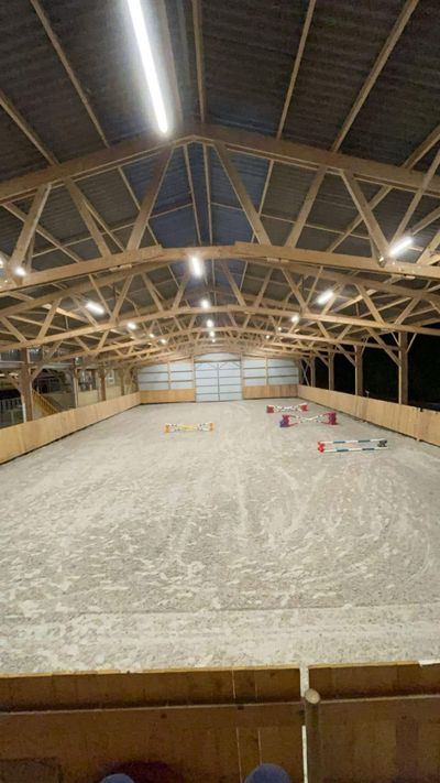 Le manège couvert éclairé en soirée, prêt pour un cours